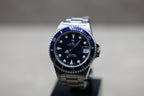 Vue macro cadran tritium Rolex Submariner collector avec couronne Rolex et fond de boîte gravé
